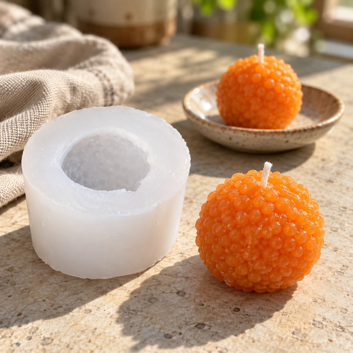 Motichoor laddu candle mould and orange wax candles in natural window light