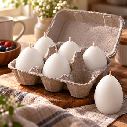 Six handmade egg shaped candles in grey egg carton and one standalone egg candle on natural wooden table