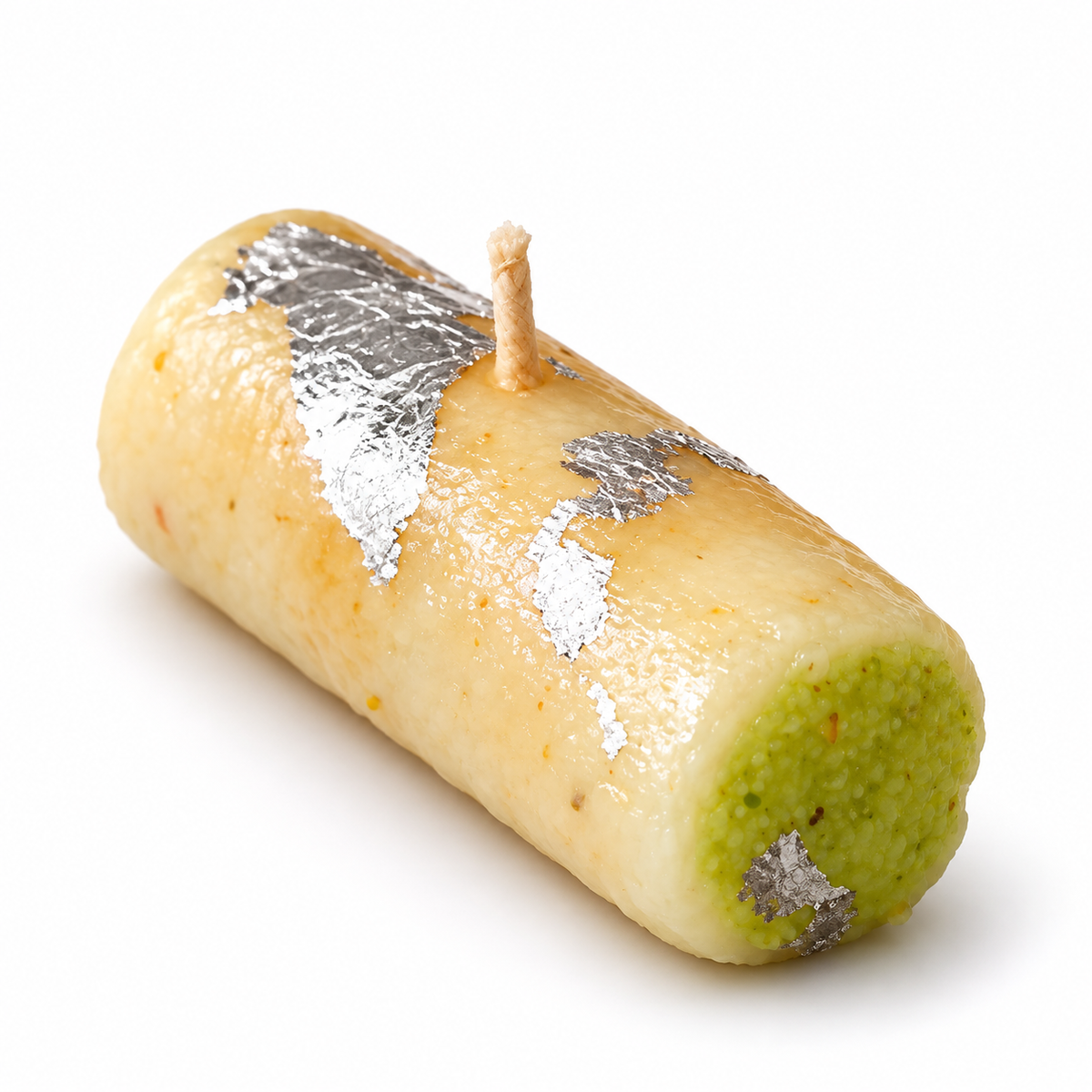 Single handcrafted Kaju Pista Roll scented candle with ivory wax cashew roll, green pistachio detail and silver varak effect on white background