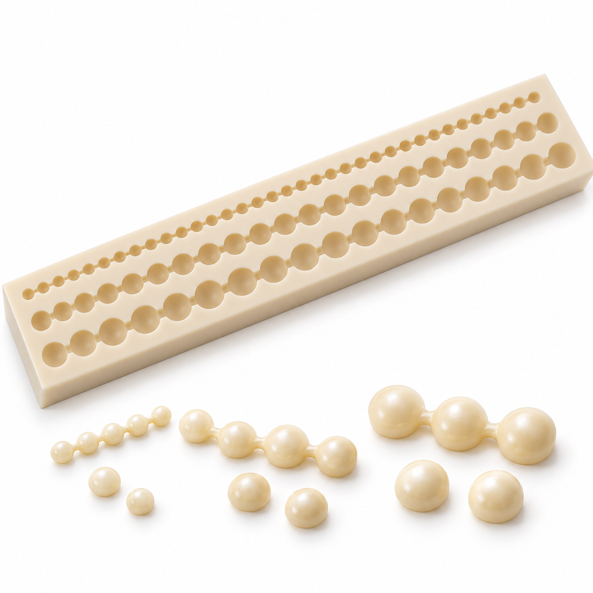 Illustrative ivory wax pearl decorations in three sizes beside the silicone mould