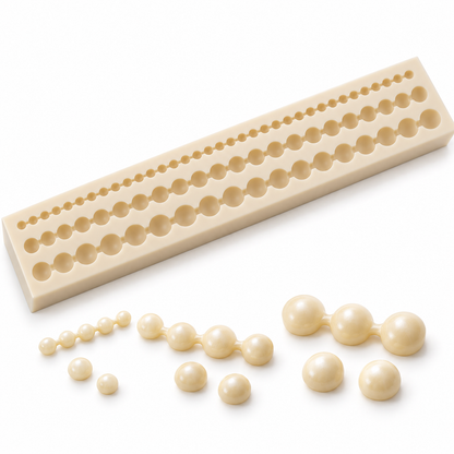 Illustrative ivory wax pearl decorations in three sizes beside the silicone mould