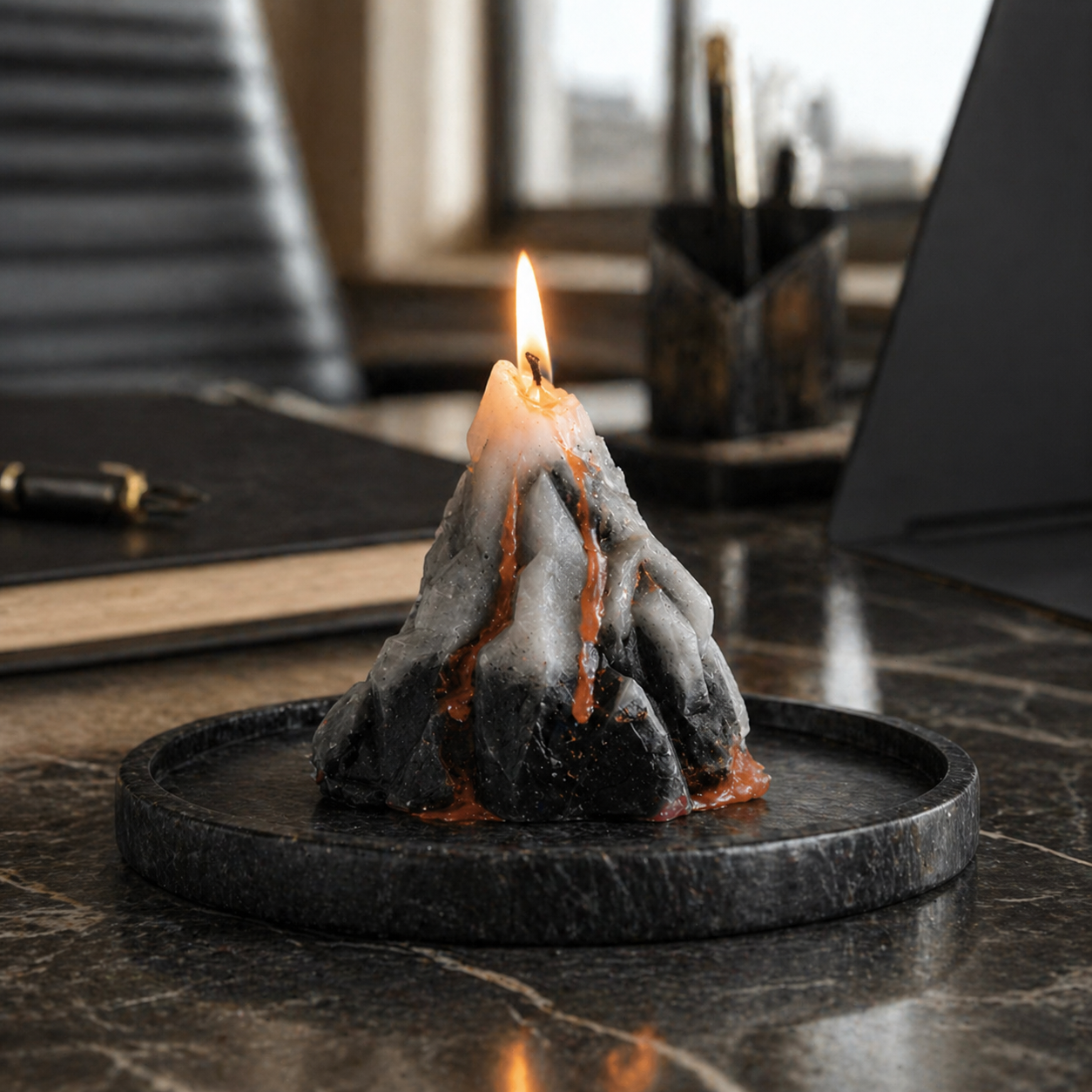 Decorative candle shaped like a volcano on a marble surface with a blurred office background.